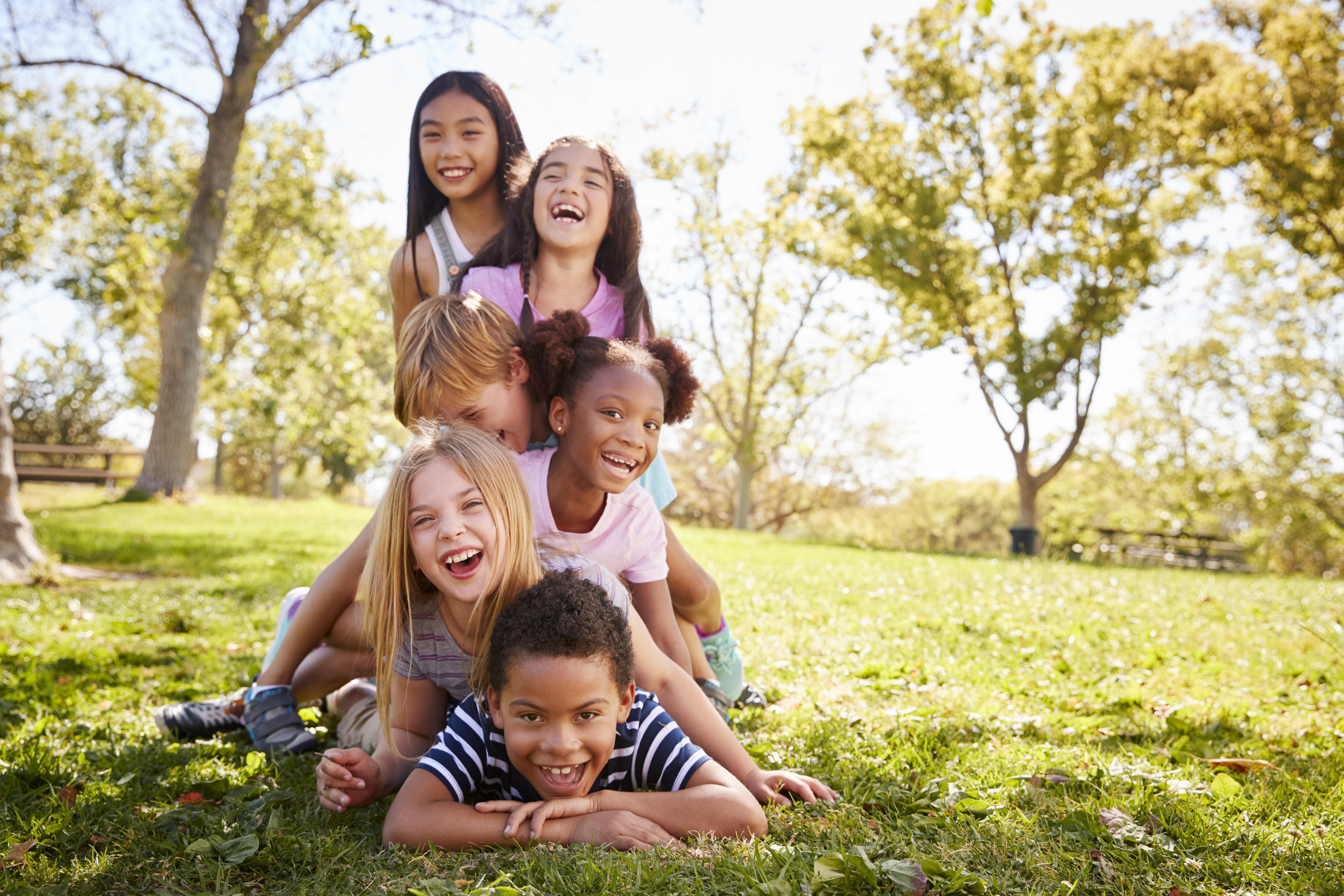 six children, piled up, laughing in the park