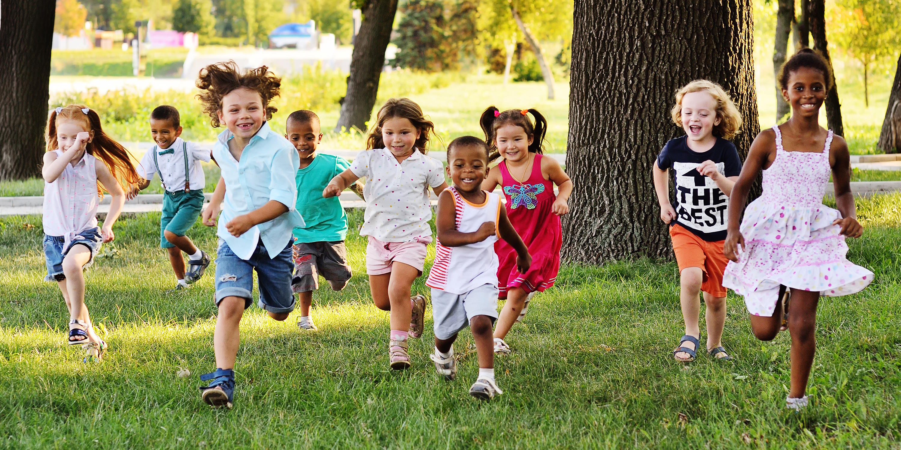 group of children running across a park 